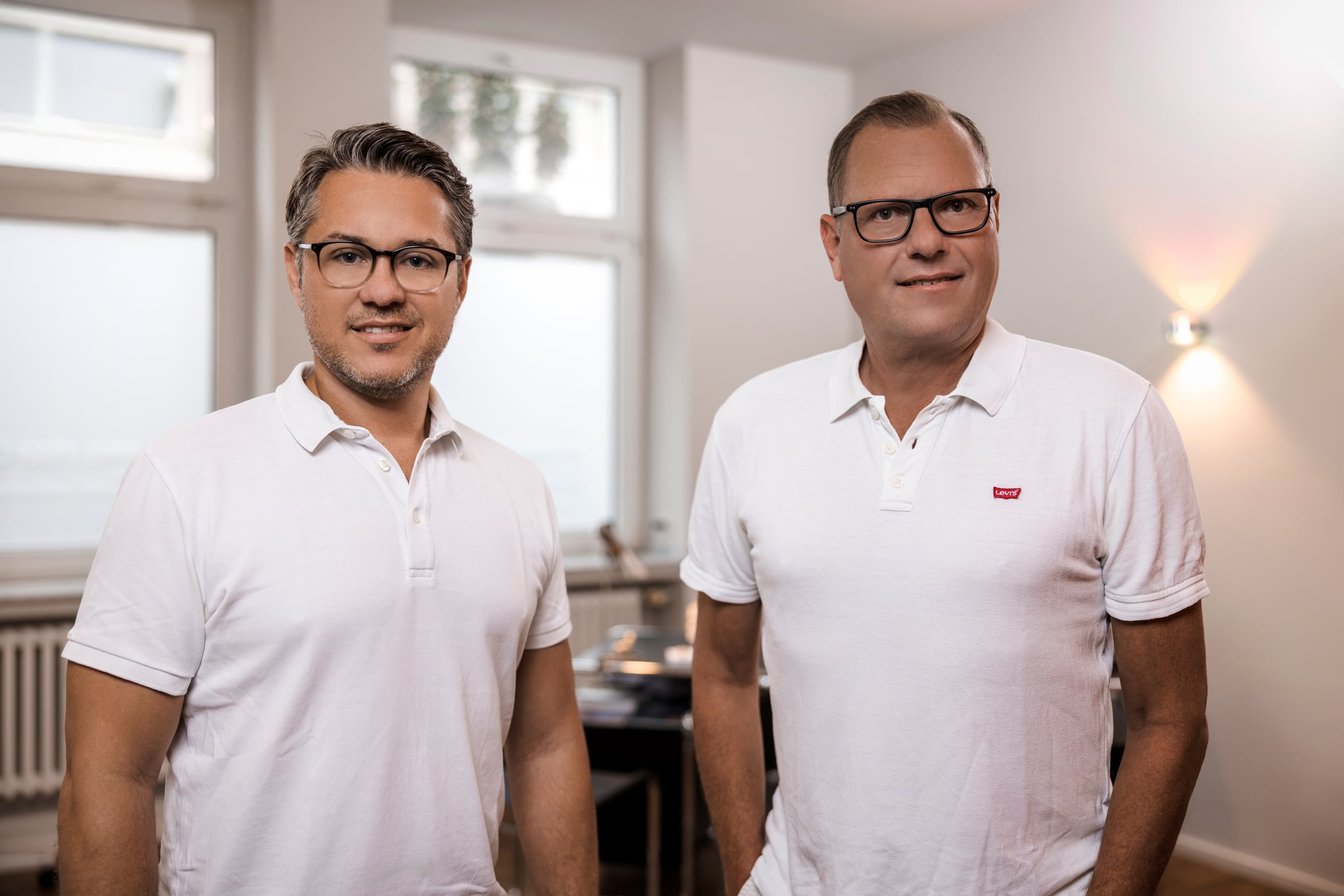 Zwei Fachärzte für Orthopädie in der Praxis, Teamporträt in weißen Poloshirts